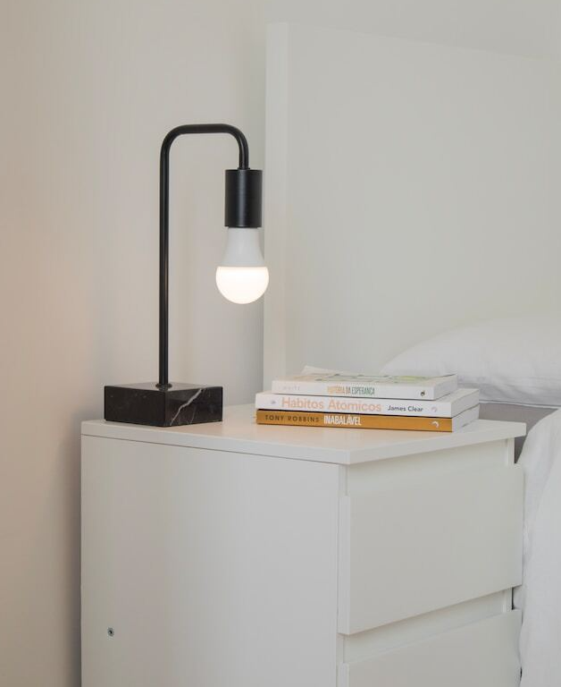 Zwarte lamp op een wit nachtkastje in een witte ruimte